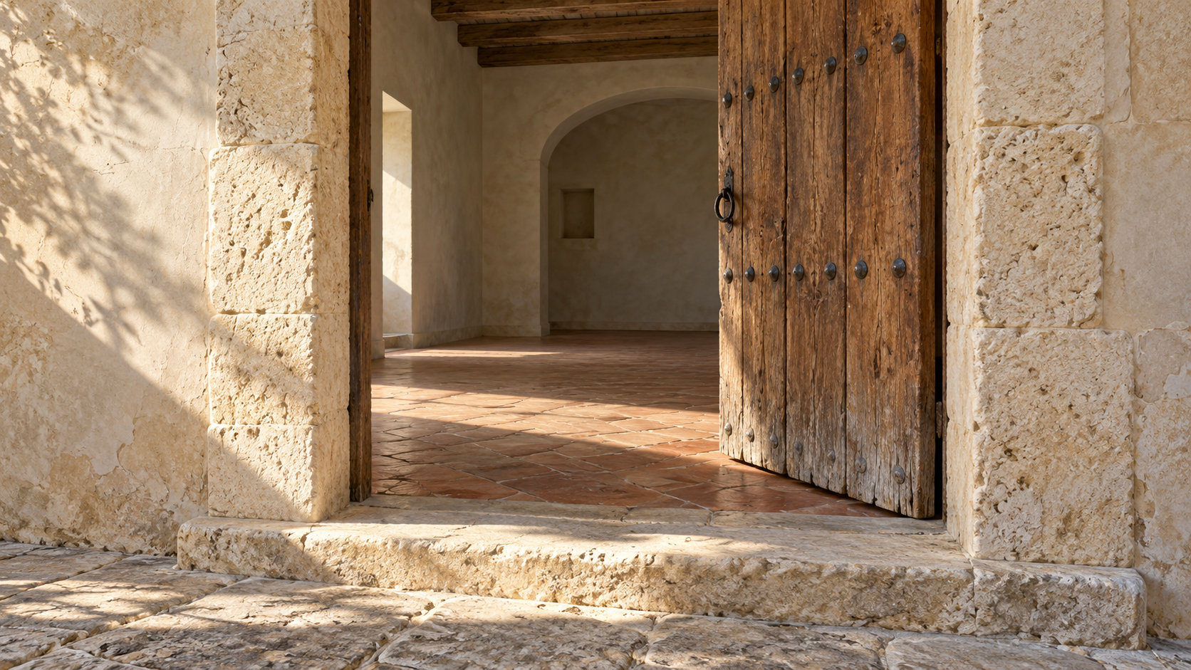 Open timber door above a worn stone threshold, leading into an empty room.